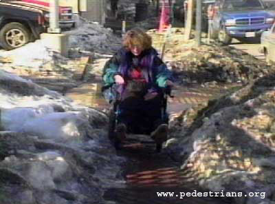 Wheelchair user attempts to use partially snow-covered sidewalk